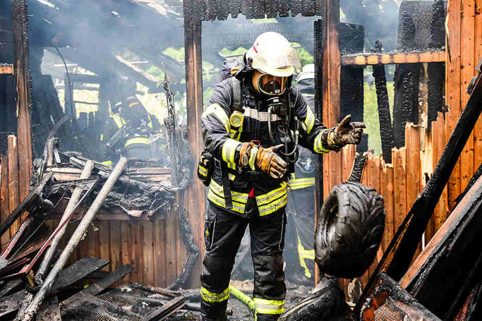 Ein Feuerwehrmann steht in dem ausgebrannten Schuppen.
