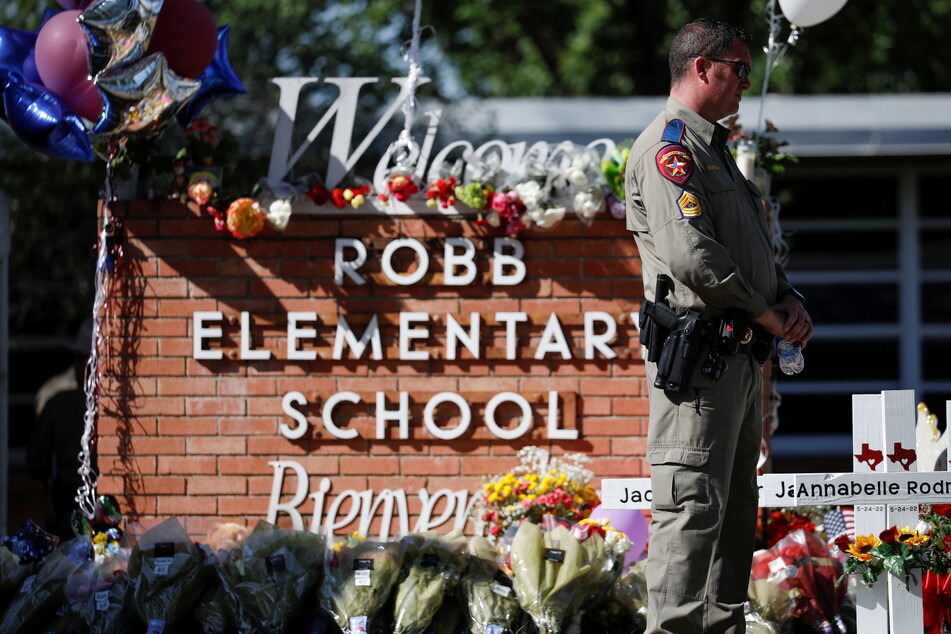 A Texas Department of Public Safety officer stands in front of a memorial outside Robb Elementary School in Uvalde, Texas.