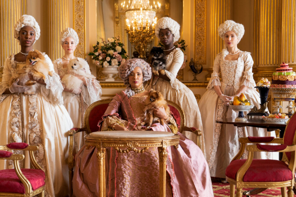 Die Kostüme, die Golda Rosheuvel (M.) als Königin Charlott und die anderen Damen tragen, sind typisch für die Serie Bridgerton.