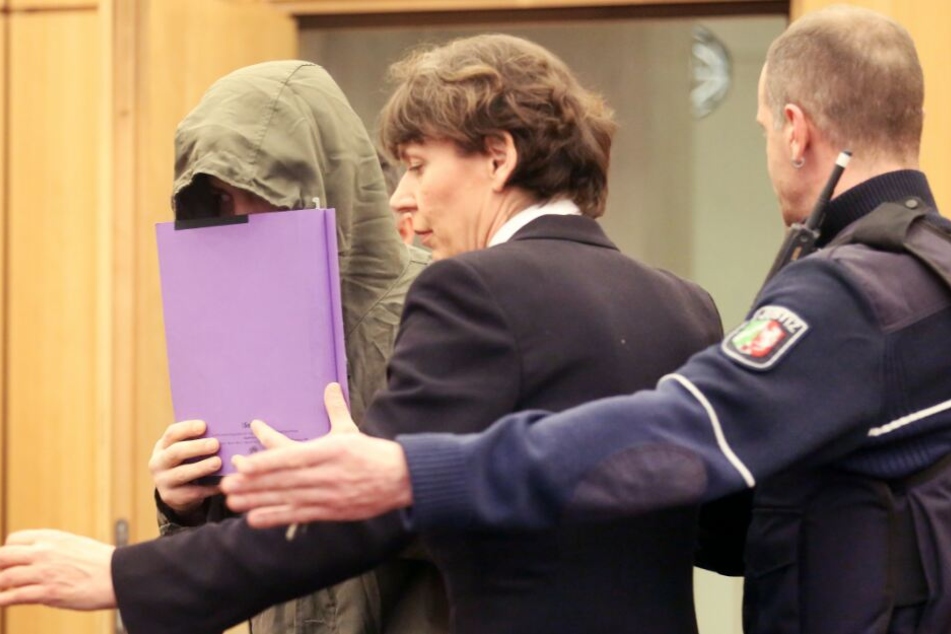Der Angeklagte (l.) wird von seiner Anwältin Susanne Tombrink und einem Justizbeamten (r.) in den Gerichtssaal geführt.