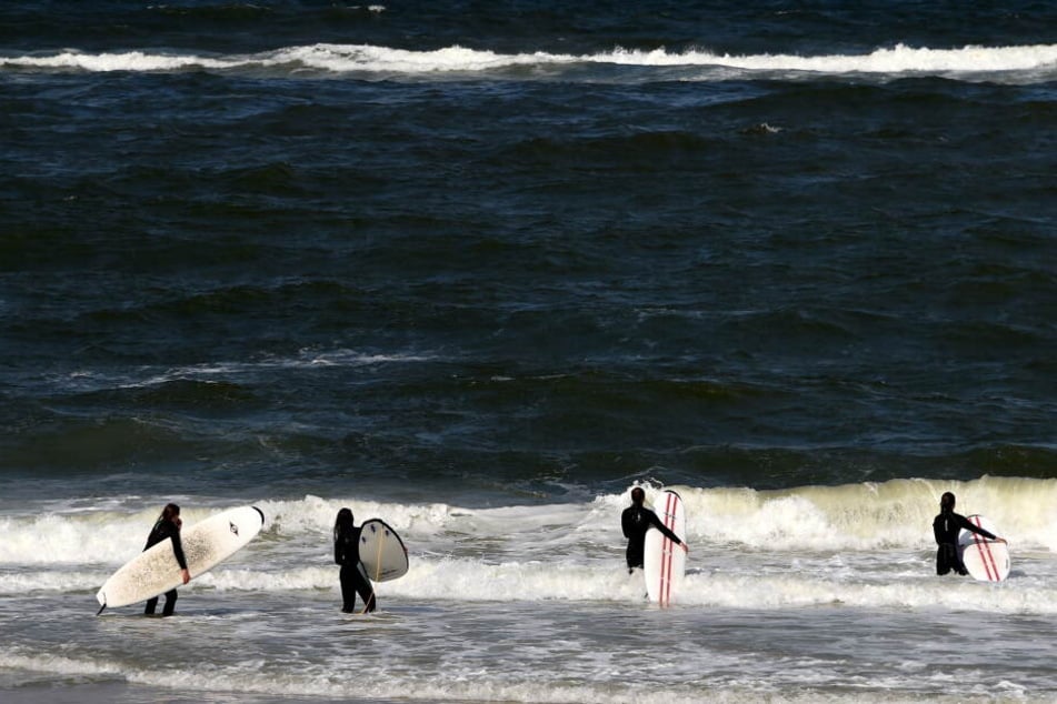 Sylt ist ein beliebter Ferienort für Surf-Fans: Hier werfen sich Teilnehmer eines Surf-Kurses am Strand von Westerland auf Sylt (Schleswig-Holstein) in die Wellen. Dank des Windes sind die Strände auf der Nordsee-Insel auch bei Kite-Surfern populär.