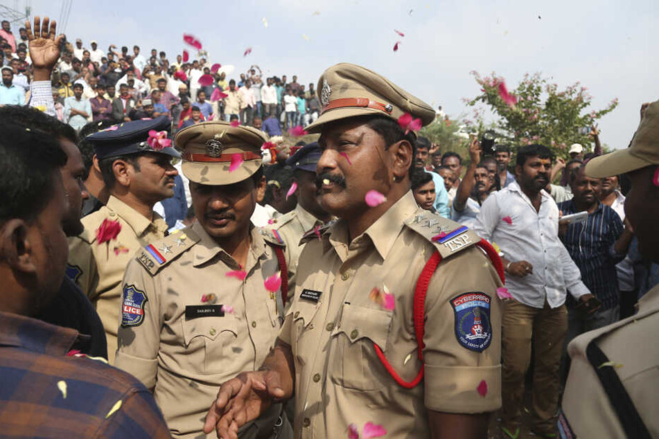 Menschen werfen Blütenblätter auf indische Polizisten.