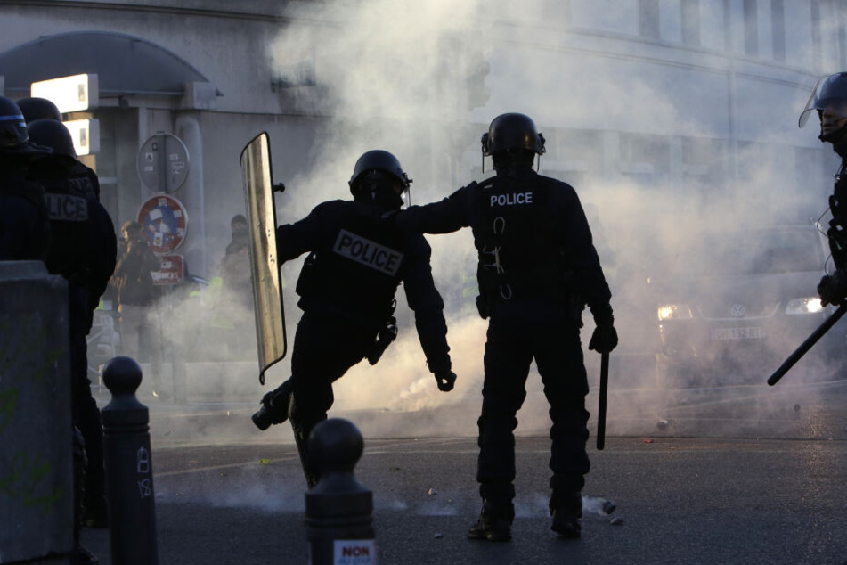 Ein Polizist tritt eine Tränengasgranate zurück.