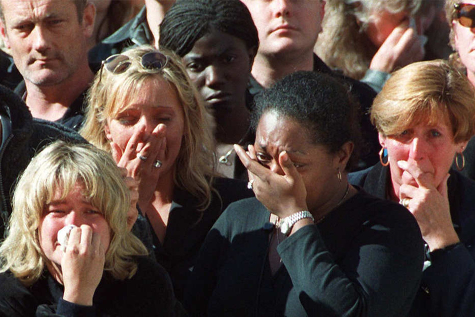Weinend verfolgen etliche Menschen am 6. September 1997 in London die Übertragung der Trauerfeier für Prinzessin Diana. In der ersten Hälfte der etwa einstündigen Feier in Westminster Abbey trug Elton John sein Diana gewidmetes Lied "Englands Rose" vor.