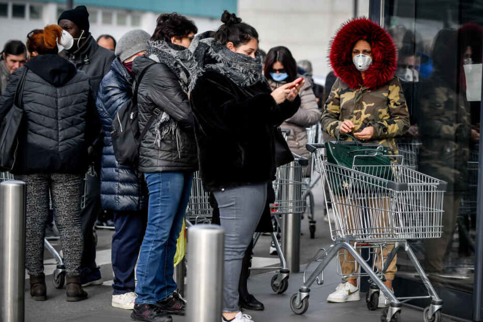 Vor einem Supermarkt stehen Kunden mit Mundschutz.
