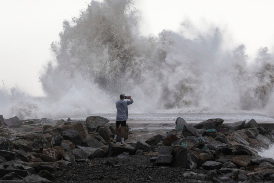 Ein Mann fotografiert durch das Wetter hervorgerufene Wasserspektakel.