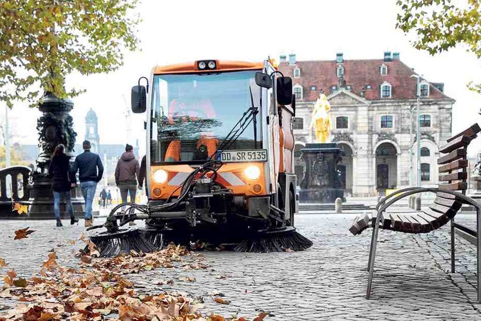 Mitarbeiter der Stadtreinigung kehren Laub, damit der Spaziergang rund um den Goldenen Reiter bei Regen nicht bald zur Schlitterpartie wird!