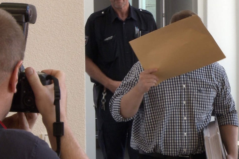 Der Angeklagte verdeckt sein Gesicht beim Prozessauftakt in Rostock. 