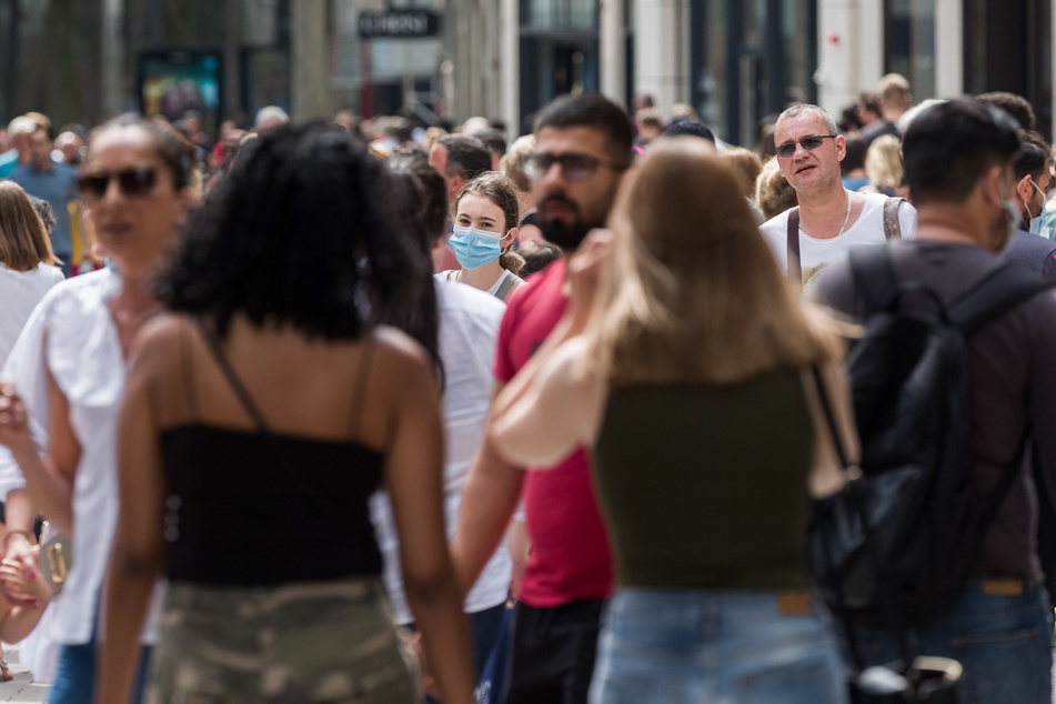 Passanten gehen bei sommerlichen Temperaturen in der Innenstadt über die Spitaler Strasse.