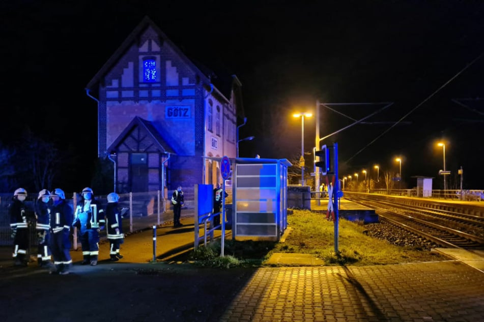 Feuerwehrleute stehen am Bahnübergang, der sich unmittelbar hinter dem Bahnhof Götz befindet.