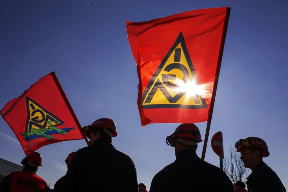 Die Fahnen der IG Metall wehen im Wind. Die Gewerkschaft schwört die Beschäftigten der sächsischen Metall- und Elektroindustrie bei den Warnstreiks am Montag auf einen harten Arbeitskampf ein.