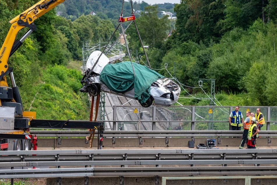 Das Autowrack wurde mit einem Kran auf die Autobahnbrücke gehoben.