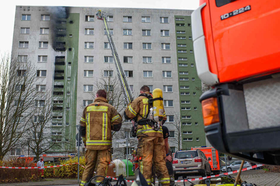 Zwei Feuerwehrmänner stehen nach ihrem Einsatz vor dem brennenden Hochhaus.