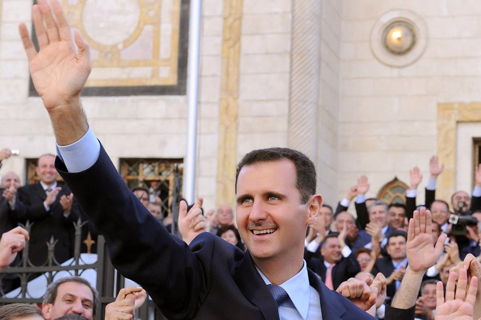 A handout file picture released by the Syrian Arab News Agency (SANA) shows Syrian President Bashar al-Assad waving at supporters after addressing parliament in Damascus on March 30, 2011.