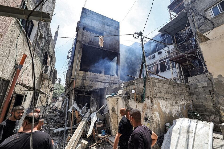 People inspect a building that was heavily damaged during an Israeli army raid on the Nur Shams camp for Palestinian refugees, east of Tulkarm in the occupied West Bank.