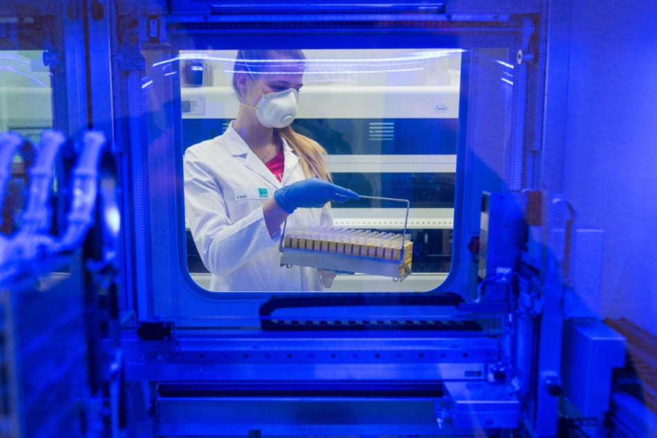 Eine Biologielaborantin bringt Proben auf das SARS-CoV-2-Virus zu einem Analysegerät.
