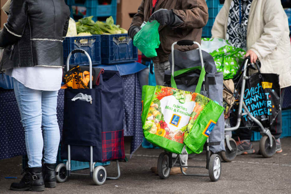 Gäste der Münchner Tafel stehen an der Ausgabestelle am Großmarkt.