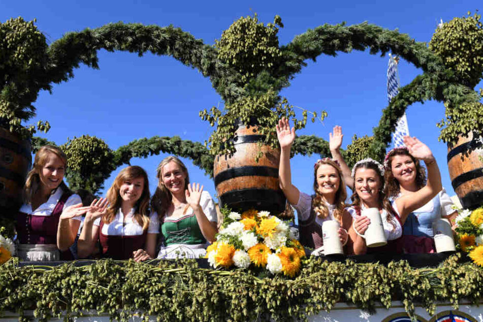 Auftakt zum Oktoberfest. Bedienungen winken beim Einzug der Festwirte auf einem geschmückten Wagen.