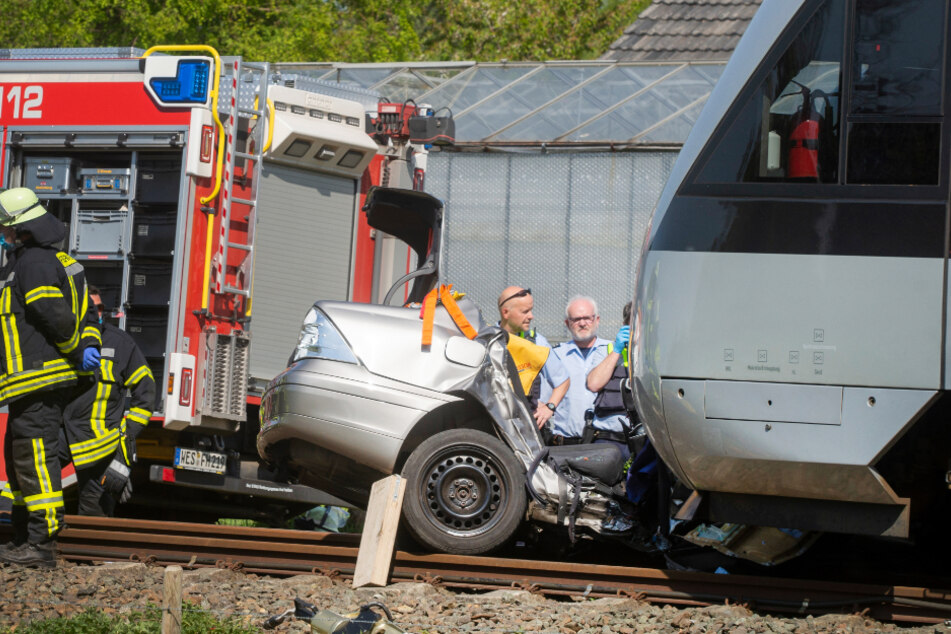 Das völlig zerstörte Auto vor einem Zug.