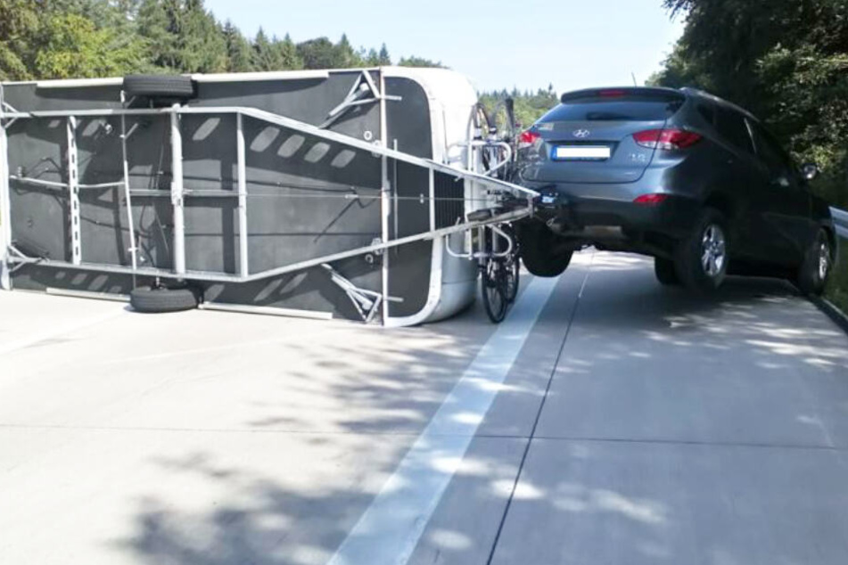 Den Einsatzkräften bot sich auf der A7 ein kurioses Bild: Der Wohnwagen-Anhänger war auf die Seite gekippt, das Auto hing in der Luft.