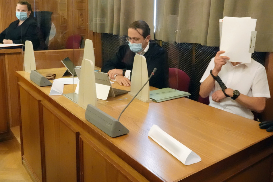 Tübingen, 22. Juli: Im Prozess am Landgericht Tübingen um ein illegales Waffenlager verdeckt der Hauptangeklagte (r.) neben seinem Anwalt sein Gesicht.