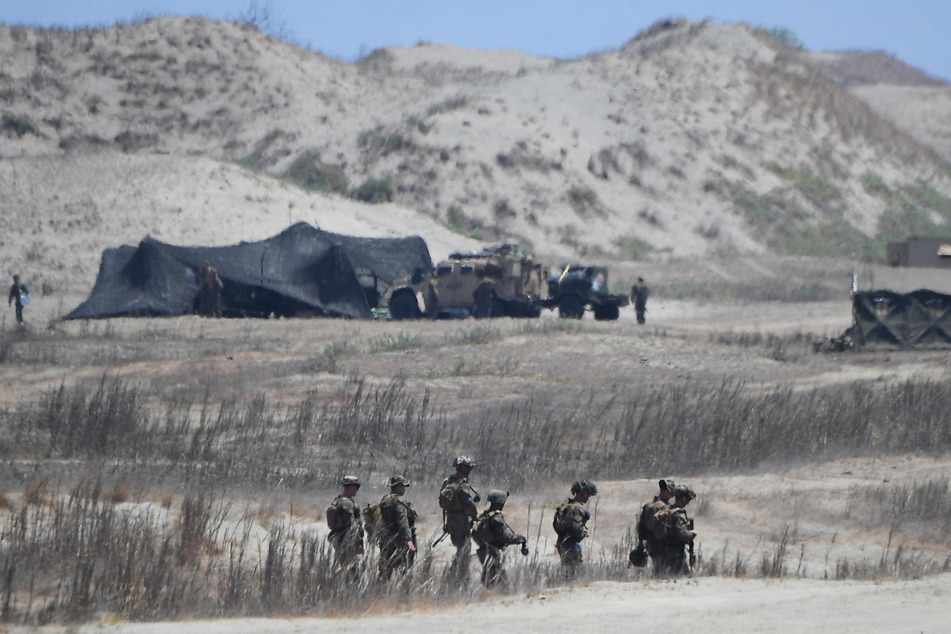 US marines walk in front of their temporary camp after watching Philippine army personnel fire their Autonomous Truck Mounted howitzer system (ATMOS), a 155 mm caliber self-propelled gun system, during the maritime strike exercise as part of the joint US-Philippines annual military Balikatan drills on May 8, 2024.