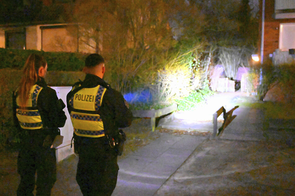 Mit lichtstarker Taschenlampe leuchten zwei Polizisten in einen Garten, immer auf der Suche nach der "vermissten Person".
