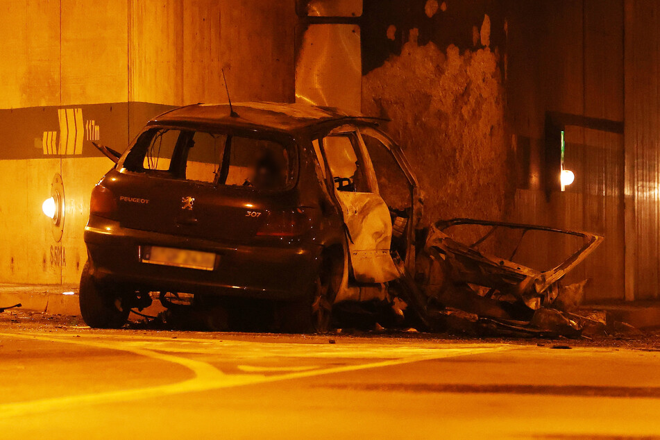 Das ausgebrannte Wrack des verunglückten Peugeot 307 steht im Düsseldorfer Rheinufer-Tunnel.