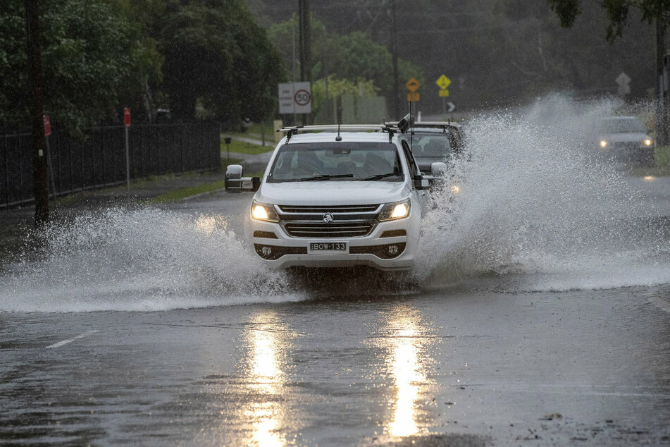 Autos fahren auf einer überschwemmten Straße in Port Stephans, Australien.