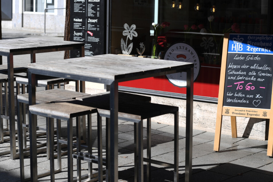 Leere Tische sind neben einem Schild eines Bistros zu sehen, in dem es nur noch "To Go" Speisen gibt. Die Gastronomie hat an der Corona-Krise zu knabbern.