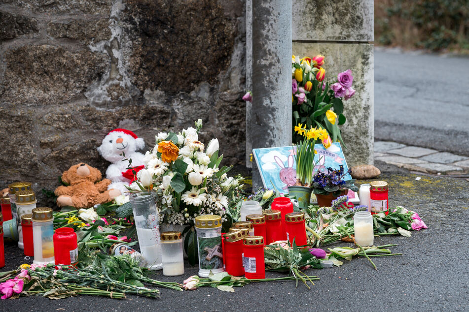 An einer Mauer vor dem Kinder- und Jugendhilfezentrum, in dem eine Zehnjährige tot aufgefunden wurde, liegen Blumen, Kuscheltiere und Kerzen.