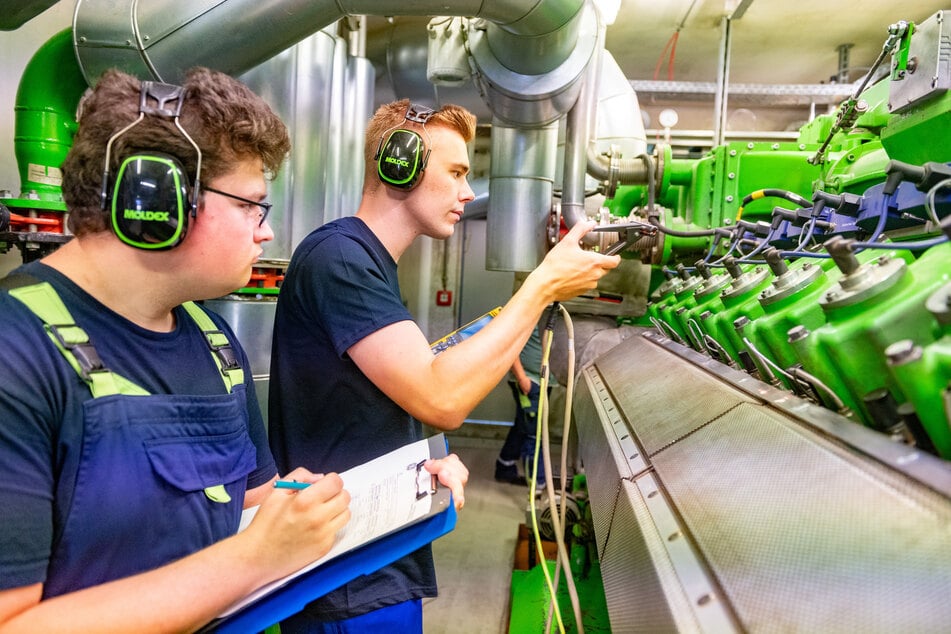 Im Blockheizkraftwerk messen Lehrling Rick (r.) und unser Mann die Zündspannung.