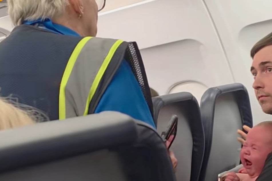 Die Flugbegleiterin erklärt Kyle, dass er das Flugzeug mit seinem Baby und seiner Partnerin Sydney Tash verlassen soll.