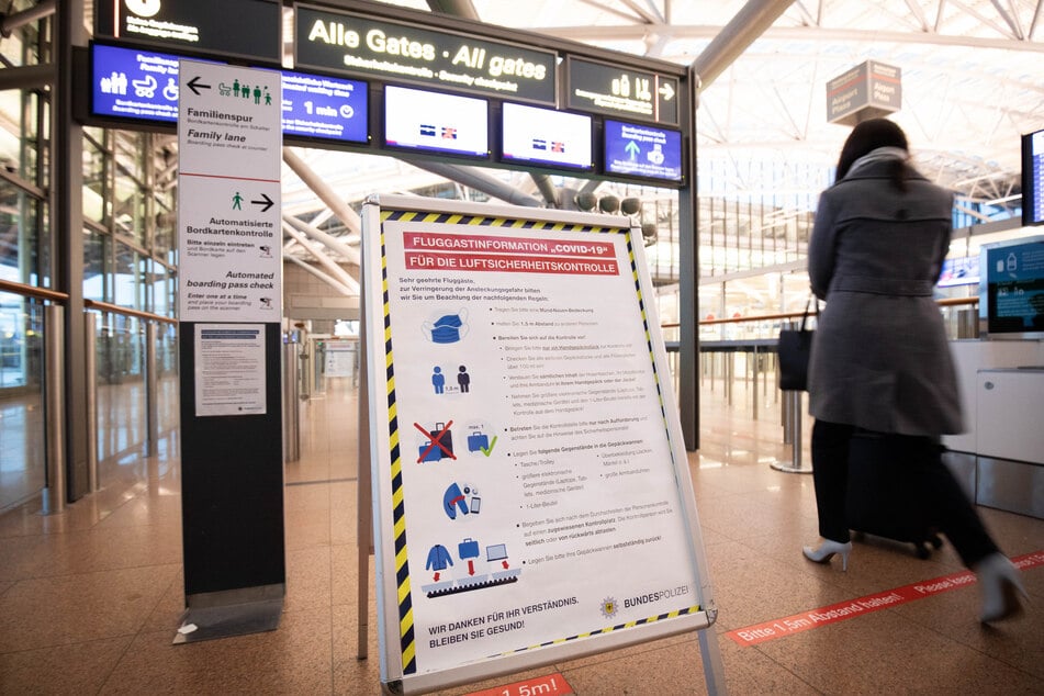 Eine Tafel mit Informationen zu Corona-Schutzmaßnahmen steht am Flughafen Hamburg.