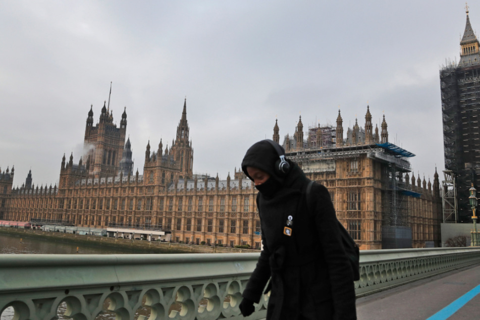 Mit Schutzmaske ist eine Frau auf der Westminister Bridge unterwegs. Die Krankenhäuser sind bereits weitgehend ausgelastet.
