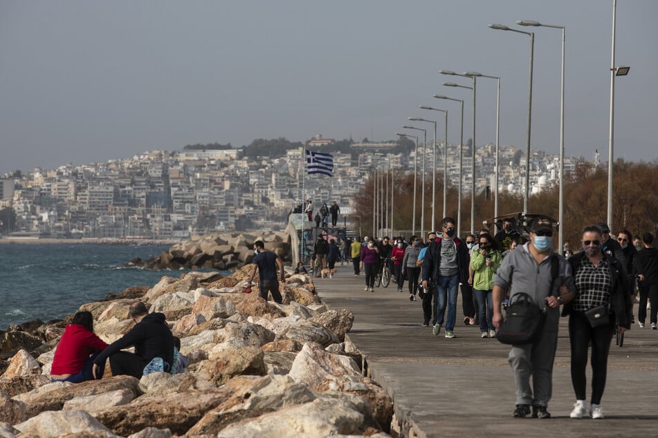 Menschen spazieren auf einer Promenade im Vorort Alimos, südlich von Athen.