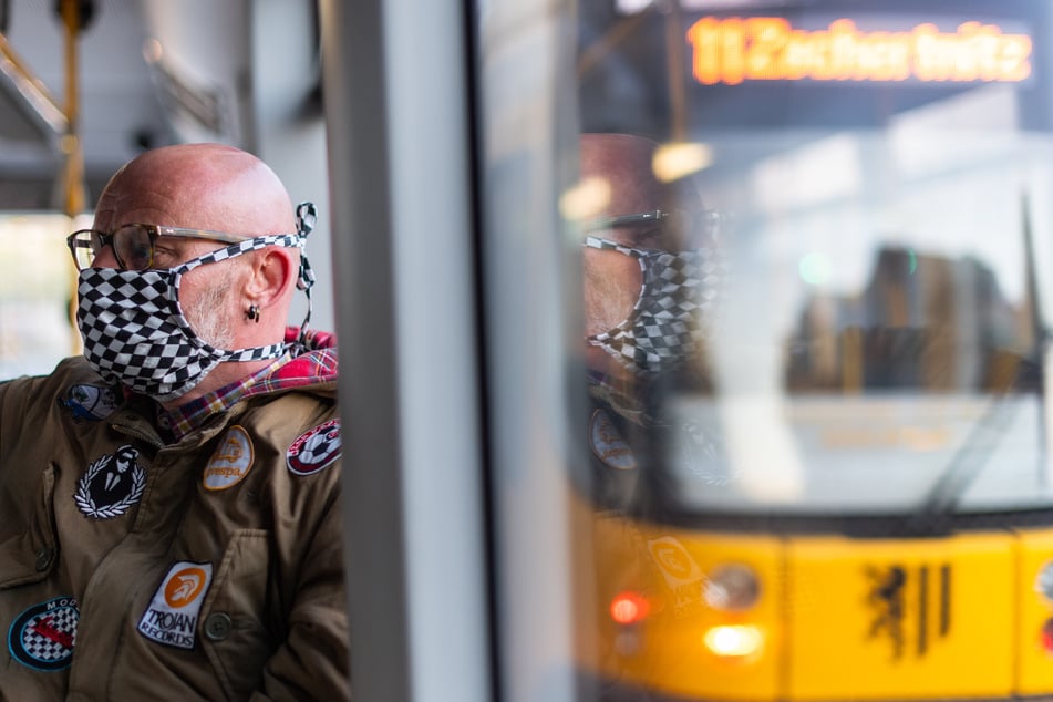 Michael Riedel, Gesundheits- und Krankenpfleger, sitzt am Morgen auf dem Weg zur Arbeit in einer Straßenbahn und trägt einen Mundschutz.