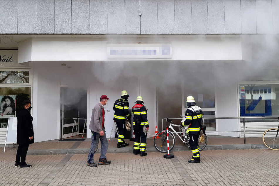 Ein Einsatzbild der Berufsfeuerwehr München: Feuerwehrleute stehen vor der betroffenen Bank.
