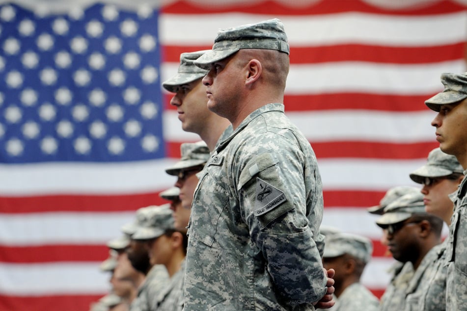 US-Soldaten stehen nach ihrer Ankunft auf der US-Airbase in Wiesbaden-Erbenheim vor einer US-Flagge. Die Zahl der US-Soldaten in Deutschland soll um fast 12.000 verringert werden.