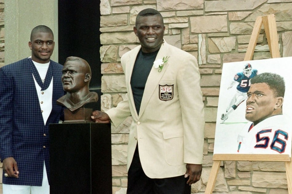 Pro Football Hall of Famer Lawrence Taylor (r.) poses with his bronze bust at the Hall of Fame Induction ceremony along with his son and presenter Lawrence Taylor Jr.