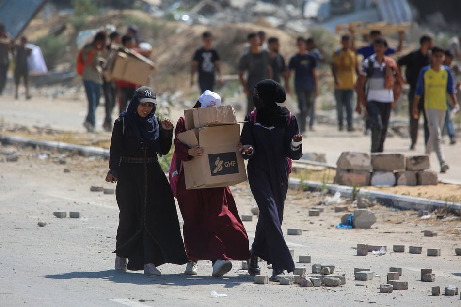 A Palestinian woman carries a box from the US-backed Gaza Humanitarian Foundation in the central Gaza Strip on August 4, 2025.