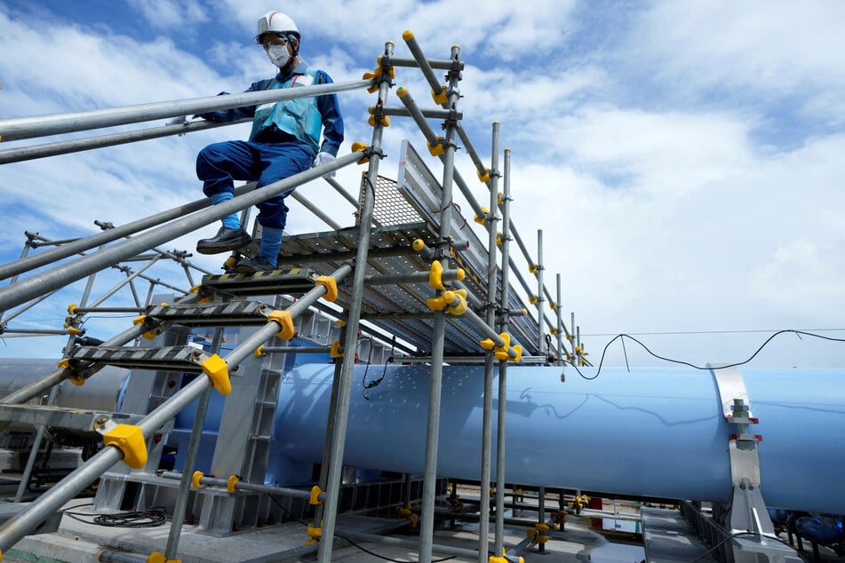 A member of staff walks near a blue pipeline at a facility for releasing treated radioactive water to sea from the Fukushima Daiichi nuclear power plant, operated by Tokyo Electric Power Company Holdings.