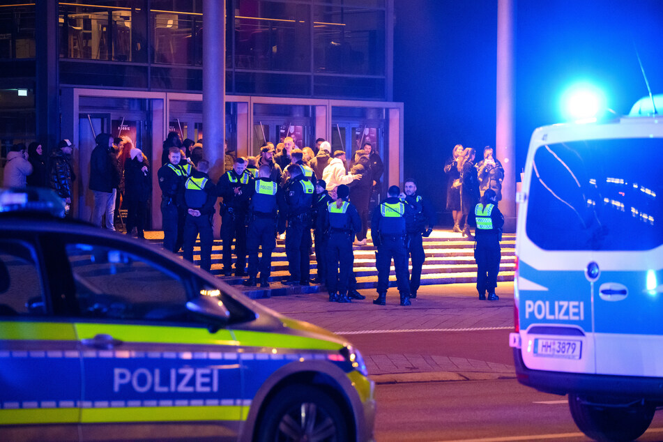 Polizisten stehen während des Einsatzes mit Besuchern vor einem Kino in Hamburg.