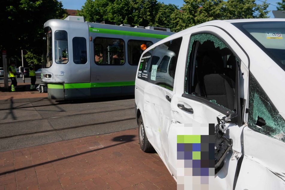 Ein kleiner Schulbus und eine Stadtbahn der Hannoverschen Verkehrsbetriebe uestra stehen nach einem Unfall an einem Bahnübergang.