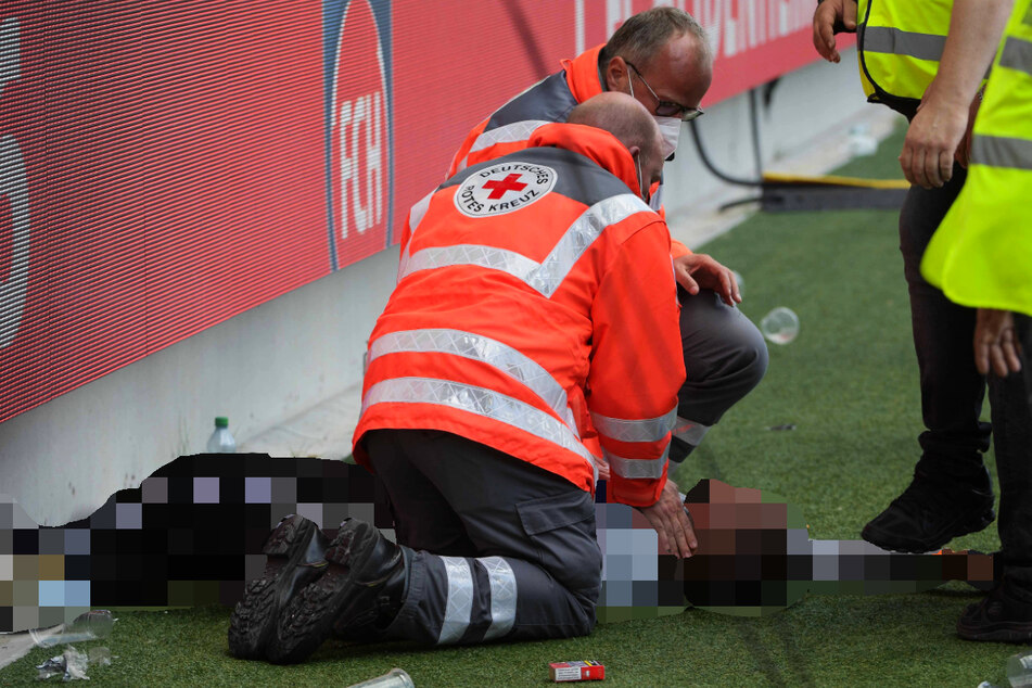 Sanitäter versorgen den bewusstlosen HSV-Fan.