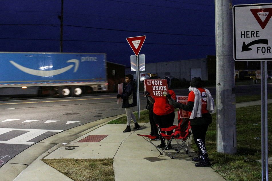 People affiliated with the RWDSU hold signs supporting unionization in front of an Alabama Amazon facility on the first day of their redo union vote.