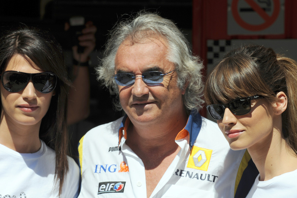 Flavio Briatore, Teamchef von Renault, steht nach einem freien Training mit zwei Models zusammen.