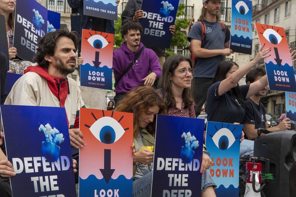 Activists carry signs during a protest warning about the destructive potential of deep-sea mining.