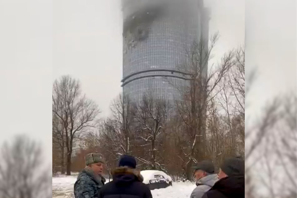 In this video grab taken from handout footage released on the official Telegram account of the Mayor's Office of Kazan on Saturday, local officials stand in front of a damaged residential building following a drone attack in Kazan.