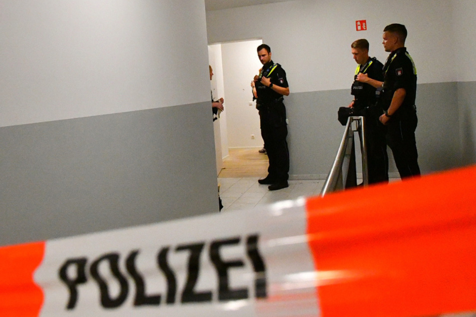 Beamte stehen vor der getroffenen Wohnungstür in Hamburg-Schnelsen.